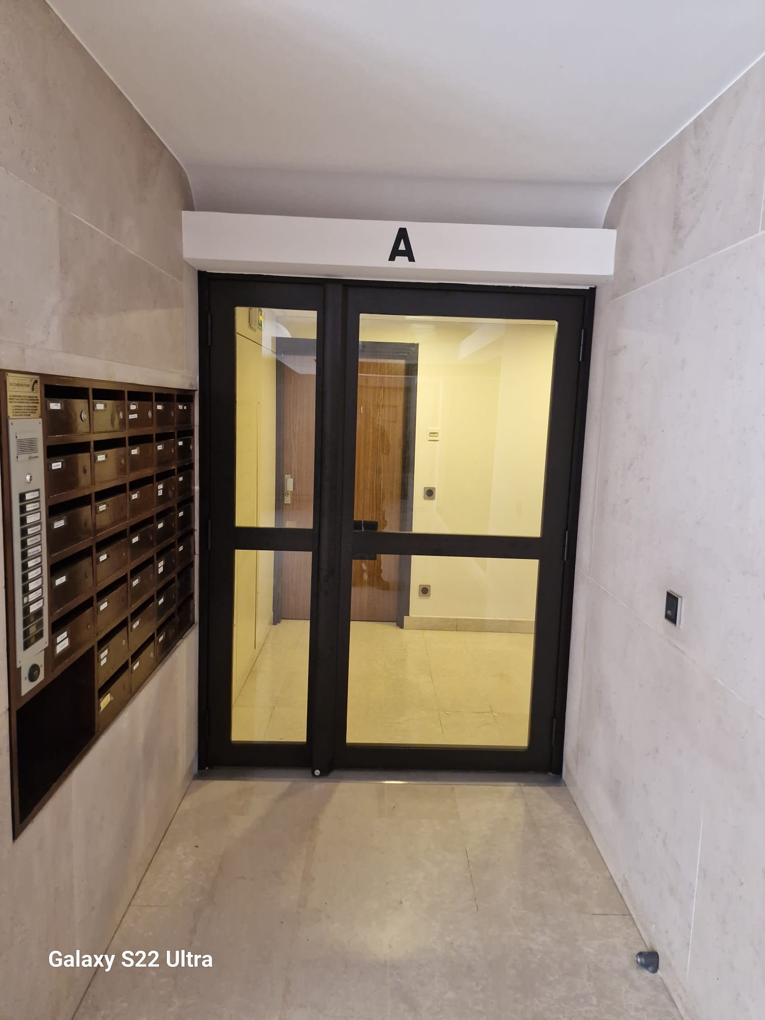 Hall d'entrée d'immeuble avec porte vitrée en aluminium noir